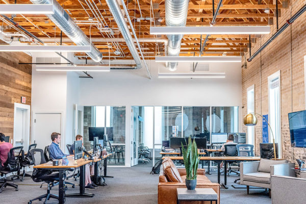 Office space with desks, people and bright lighting.